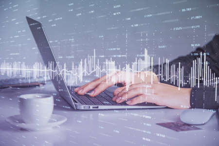 Double exposure of businesswoman hands typing on computer and forex graph hologram drawing....