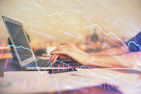Double exposure of businesswoman hands typing on computer and forex chart hologram drawing....
