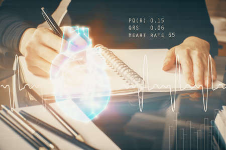 Heart hologram over womans hands writing background. Concept of Medical study. Multi exposure