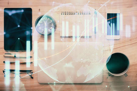 Double exposure of forex graph hologram over desktop with phone. Top view. Mobile trade platform...