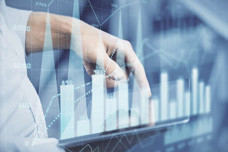 Double exposure of mans hands holding and using a digital device and forex graph drawing. Financial market concept.の写真素材