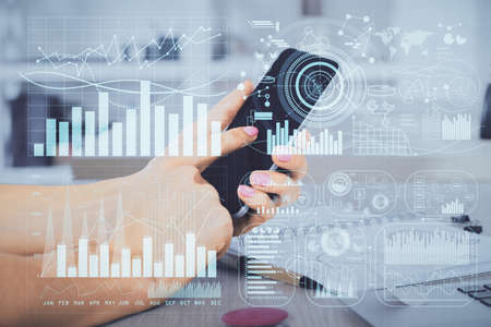 Double exposure of mans hands holding and using a digital device and forex graph drawing. Financial...
