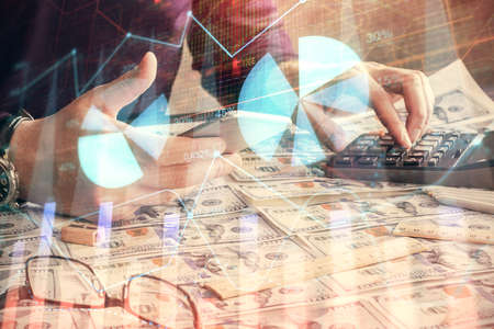Double exposure of mans hands holding and using a digital device and forex graph drawing. Financial...