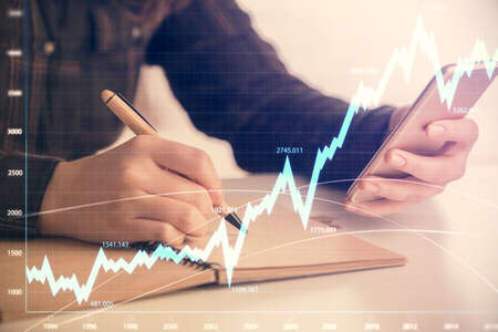 Double exposure of forex graph sketch hologram and woman holding and using a mobile device. Stock...