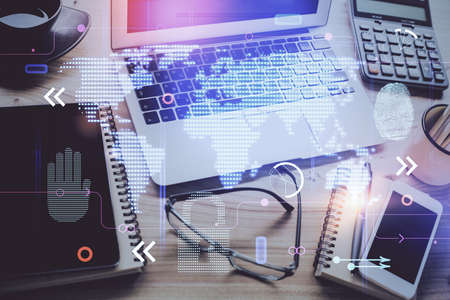 Double exposure of desktop with computer and world map hologram. International data network concept.