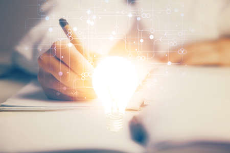 Bulb hologram over hands taking notes background. Concept of idea. Double exposureの写真素材