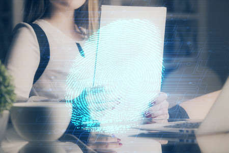 Blue fingerprint hologram over womans hands taking notes background. Concept of protection. Double...