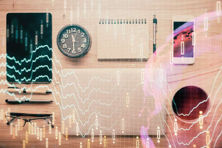 Double exposure of forex graph hologram over desktop with phone. Top view. Mobile trade platform...
