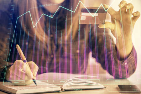 Multi exposure of woman on-line shopping holding a credit card and financial graph drawing. Stock...