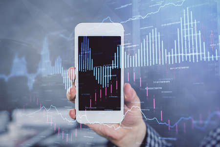 Double exposure of mans hands holding and using a digital device and forex graph drawing. Financial...