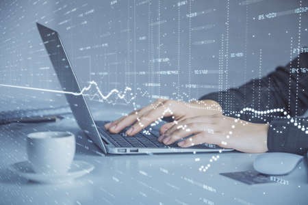 Double exposure of businesswoman hands typing on computer and forex graph hologram drawing. Financial analysis concept.の写真素材