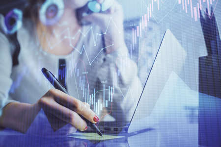 Double exposure of woman hands typing on computer and financial graph hologram drawing. Stock market...