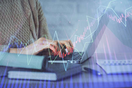 Double exposure of woman hands typing on computer and forex chart hologram drawing. Stock market...