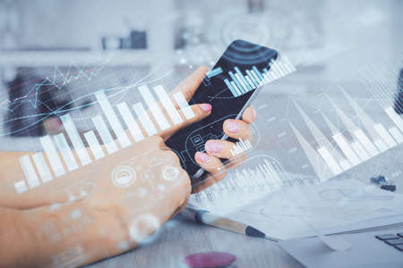Double exposure of mans hands holding and using a digital device and forex graph drawing. Financial market concept.の写真素材