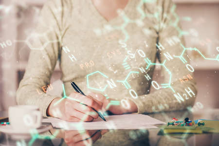 Science formula hologram over womans hands taking notes background. Concept of study. Multi exposureの写真素材