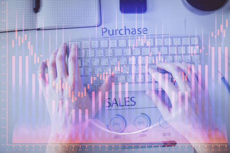 Double exposure of mans hands typing over laptop keyboard and forex chart hologram drawing. Top...