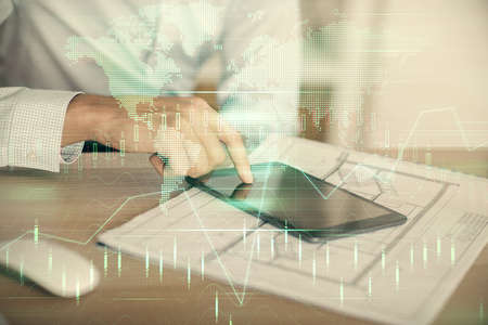 Double exposure of mans hands holding and using a digital device and forex graph drawing. Financial...