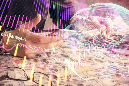 Double exposure of mans hands holding and using a digital device and forex graph drawing. Financial...