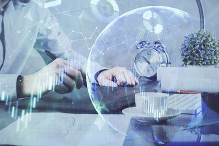 Double exposure of mans hands holding and using a phone and financial graph drawing. Analysis...