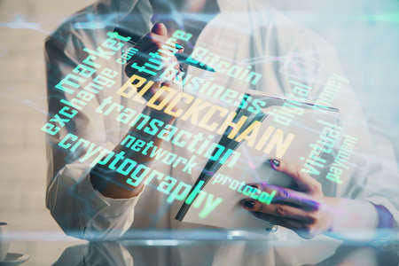 Cryptocurrency hologram, bitcoin, ico theme over hands taking notes background. Concept of blockchain. Multi exposureの写真素材