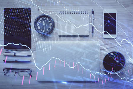 Double exposure of forex graph hologram over desktop with phone. Top view. Mobile trade platform...