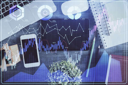 Double exposure of forex chart hologram over desktop with phone. Top view. Mobile trade platform...