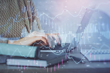 Double exposure of woman hands typing on computer and forex chart hologram drawing. Stock market...