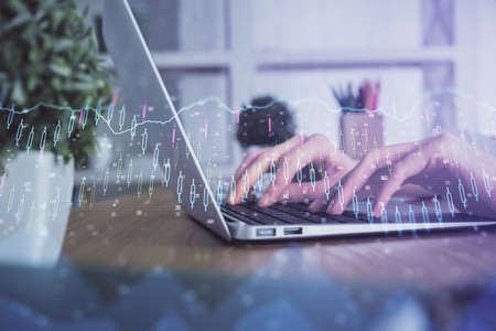 Double exposure of woman hands typing on computer and forex chart hologram drawing. Stock market invest concept.の写真素材