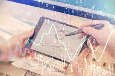 Double exposure of mans hands holding and using a phone and financial chart drawing. Market analysis...