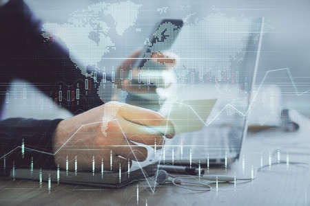 Double exposure of mans hands holding and using a phone and financial graph drawing. Analysis...