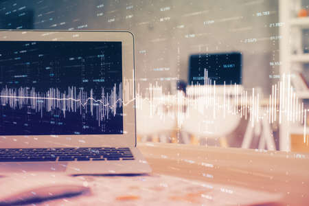 Stock market chart hologram drawn on personal computer background. Double exposure. Concept of investment.の写真素材
