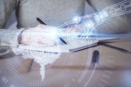Double exposure of womans writing hand on background with brain hud. Concept of learning.