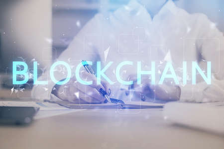 Cryptocurrency hologram, bitcoin, ico theme over hands taking notes background. Concept of...