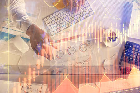 Multi exposure of mans hands typing over computer keyboard and forex graph hologram drawing. Top...