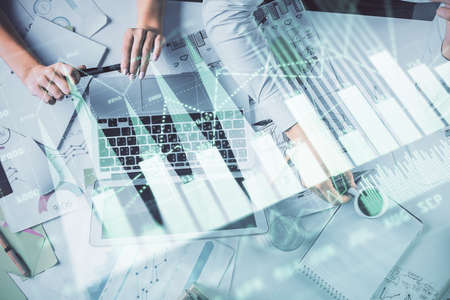 Double exposure of man and woman working together and financial graph hologram. Business concept....