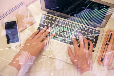 Double exposure of woman hands working on computer and forex graph hologram drawing. Top View....