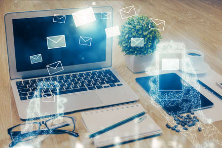 Desktop computer background in office and flying envelops hologram drawing. Double exposure. Electronic mail concept.の写真素材