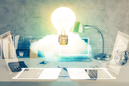 Computer on desktop in office with bulb icon hologram. Double exposure. Concept of idea.の写真素材