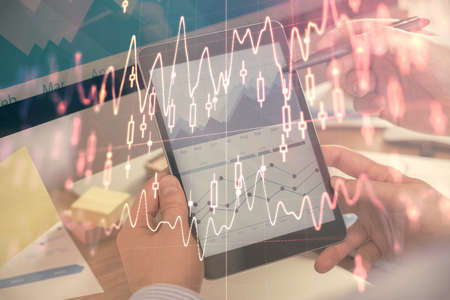 Double exposure of mans hands holding and using a phone and financial chart drawing. Market analysis...