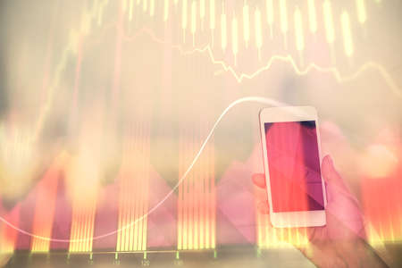 Double exposure of forex chart sketch hologram and woman holding and using a mobile device. Stock...