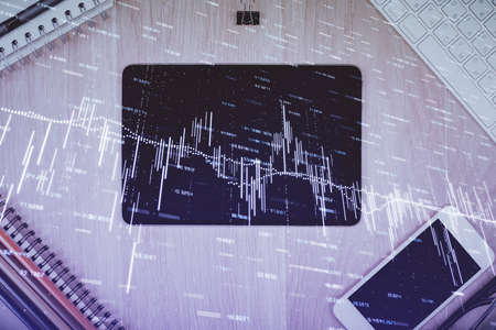 Double exposure of forex graph hologram over desktop with phone. Top view. Mobile trade platform...