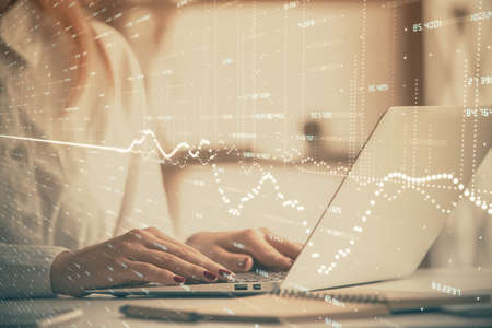 Double exposure of woman hands working on computer and forex graph hologram drawing. Financial...