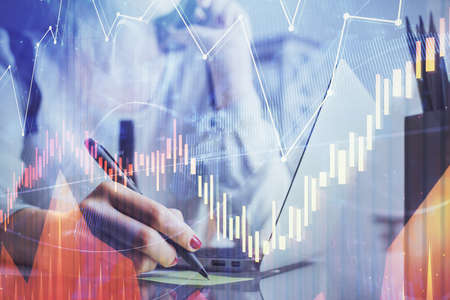 Double exposure of woman hands typing on computer and financial graph hologram drawing. Stock market...