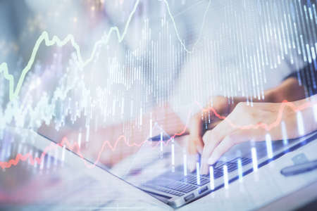 Double exposure of woman hands typing on computer and forex chart hologram drawing. Stock market...