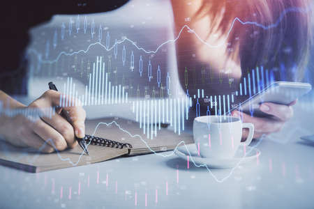 Double exposure of forex graph sketch hologram and woman holding and using a mobile device. Stock...
