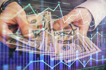 Multi exposure of financial graph drawing hologram and USA dollars bills and man hands. Analysis...