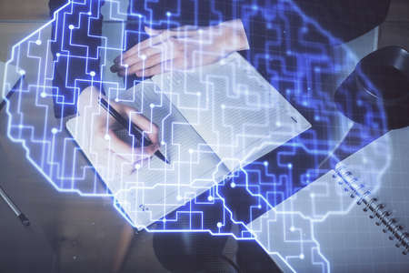 Double exposure of writing hand on background with brain hologram. Concept of learning.の写真素材