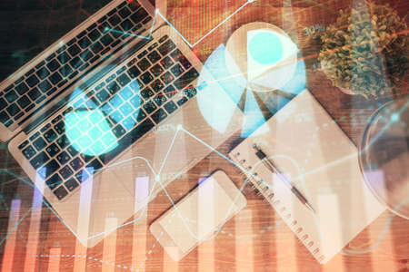 Financial market graph and top view computer on the desktop background. Double exposure. Investment...