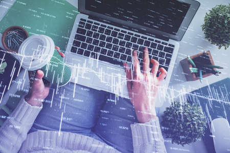 Double exposure of woman hands working on computer and forex chart hologram drawing. Top View....