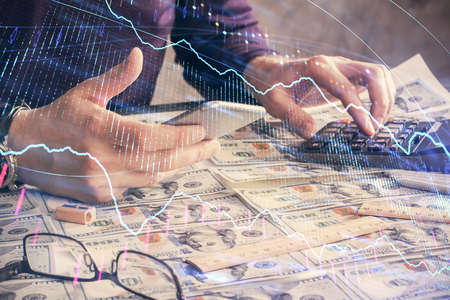 Double exposure of mans hands holding and using a digital device and forex graph drawing. Financial market concept.の写真素材